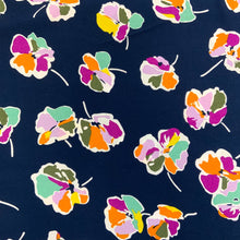 Load image into Gallery viewer, A beautiful floral motif design blocked with colours in light green, orange, pink and yellow incased in a white outline all against a navy background. Viscose fabric is a semi-synthetic type of Rayon, made from wood pulp it gives a smooth silk like finish and as a light weight fabric will drape well across the body. It makes it an ideal sewing fabric because of it’s versatility, and perfect for a number of sewing projects, including dresses, skirts, blouses and summer trousers to name a few. 
