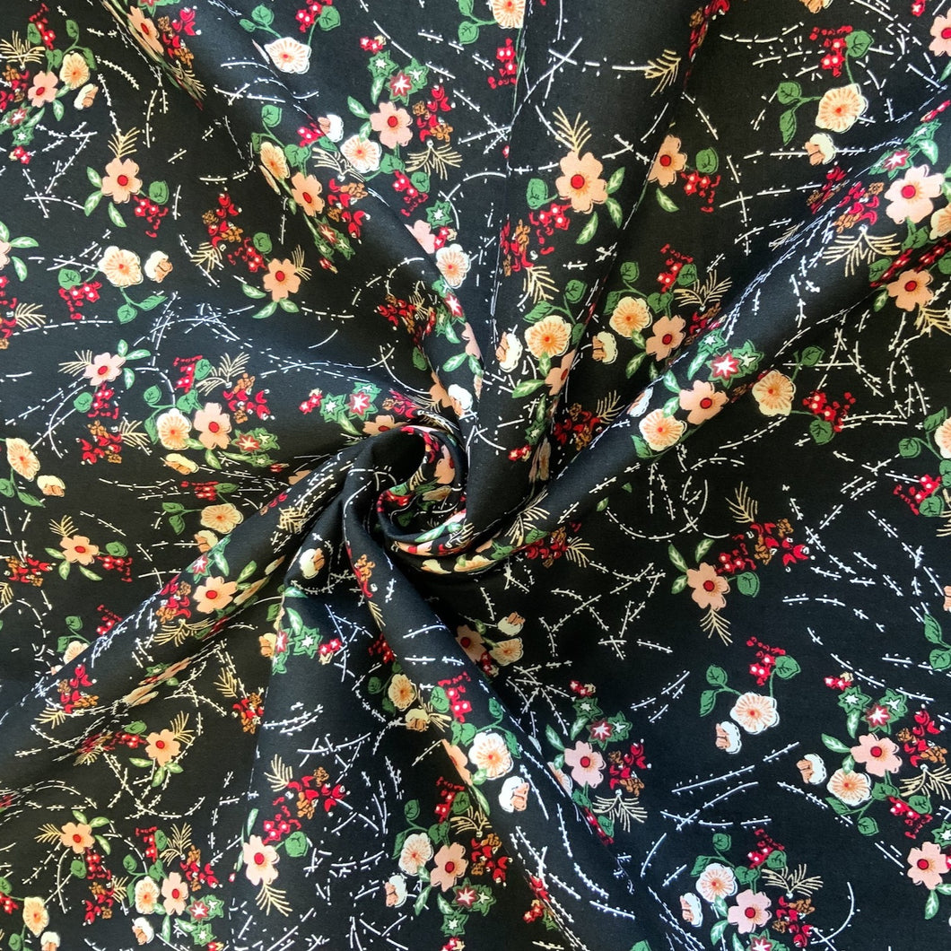 A cotton poplin fabric with a floral bouquet inspired design. The fabric has flowers in peach and white with little red flowers and green leaves against a black background and white lines and dashes between each bouquet. Cotton poplin has a smooth handle and a slight drape, it would be a perfect sewing fabric for dressmaking projects or craft.