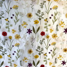 Load image into Gallery viewer, A cotton poplin fabric with a theme of wild flowers. The design has wonderful flowers with colours in yellows and reds against a crisp white background. The cotton poplin has a smooth handle and a slight drape, it would be a perfect sewing fabric for dressmaking projects or craft.
