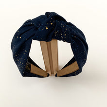 Load image into Gallery viewer, Introducing a wonderful collection of hairbands created by the lovely Northstar Needlework brand. All the knotted top hairbands are handmade with a double layer of beautiful fabric. This particular design has beautiful gold speckles against a navy background.
