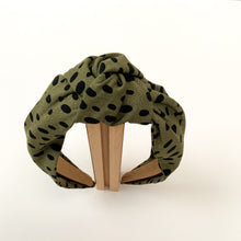 Load image into Gallery viewer, Introducing a wonderful collection of headbands created by the lovely Northstar Needlework brand. All the knotted top hairbands are handmade with a double layer of beautiful fabric. This particular design is a beautiful olive green fabric with black polka dots.
