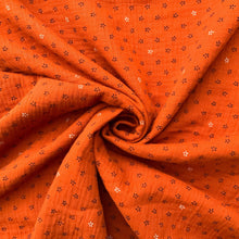 Load image into Gallery viewer, Double Fabric with stencil flowers in black and randomly placed white flowers on a rich burnt orange background. Perfect for sewing and dressmaking
